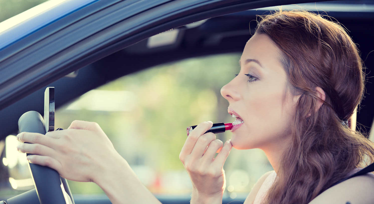 woman putting lipstick on in car